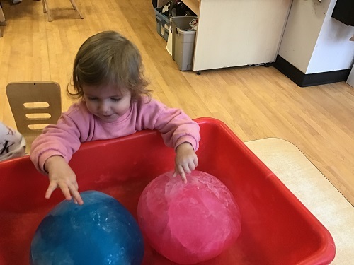 Toddler exploring two large ice balls