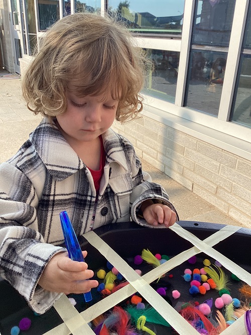 A child exploring with pompoms on the playground.