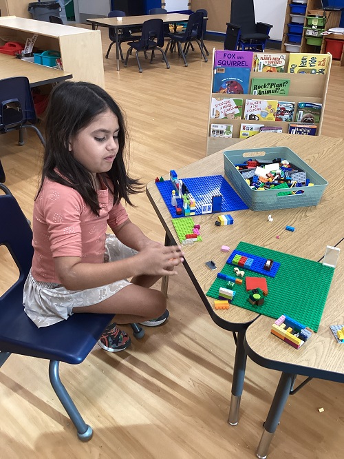 A child sitting at a table building with lego.