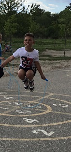 child jumping with a skipping rope, both legs tucked under him 