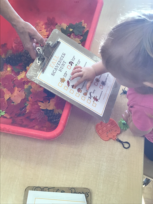 child looking at a list of fall items to find on a scavenger hunt