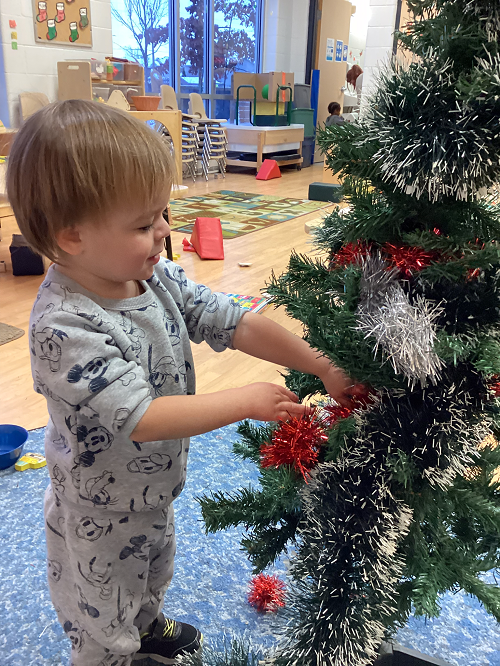 child decorating a christmas tree