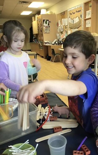Child using straws and sticks for pig house