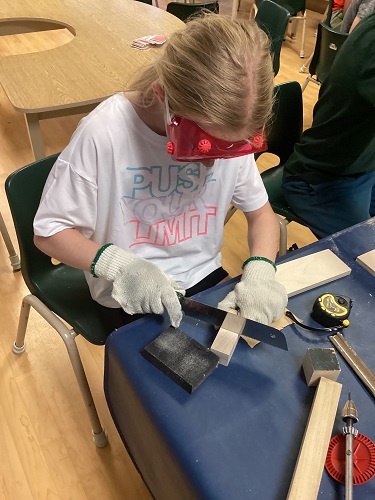 Child using saw to cut wood