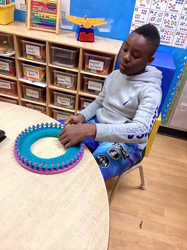 school-age boy completing his knit loom