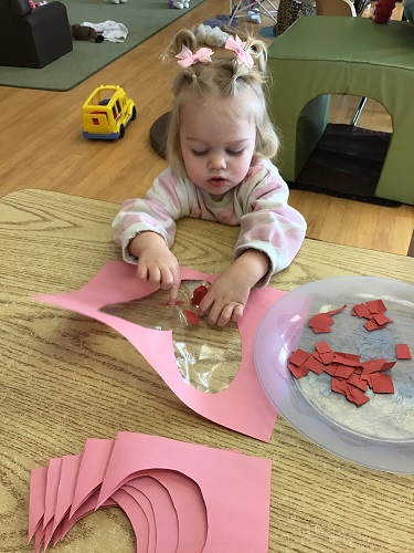 Toddler girl focusing on filling heart up with pieces