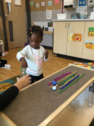 A child putting beads in and out of a plastic bottle