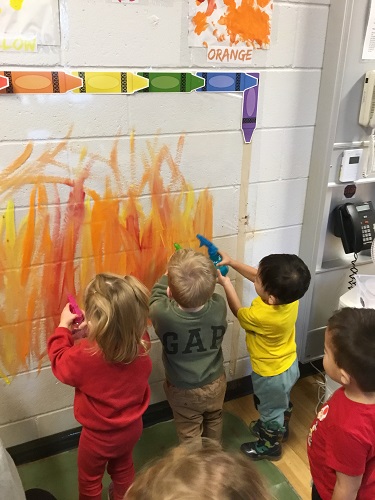 Children using spray bottles to squirt water on the painted wall