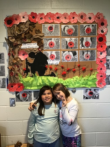 Two children standing in front of a Remembrance Day display