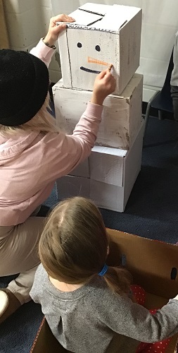 An educator colouring on a painted white box stacked as a snowman