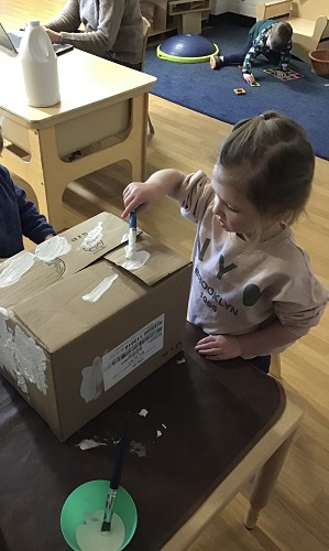 A child painting a cardboard box