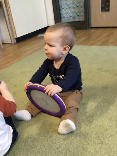 A child holding a large flat drum