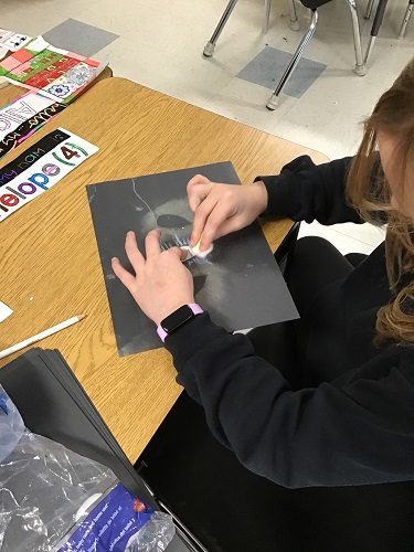 A child at a table colouring with chalk