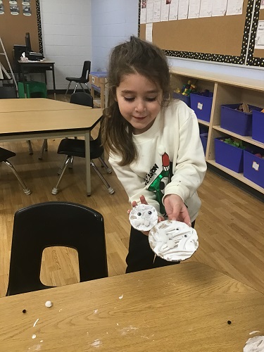 A child showing off her cardboard snowman she created