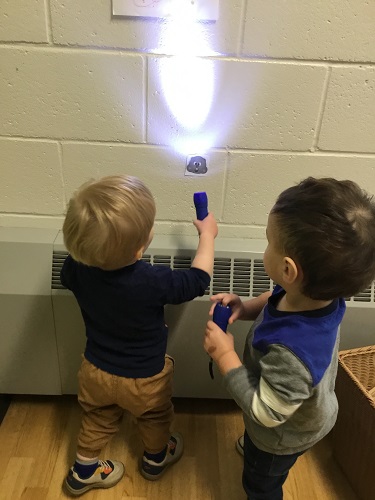 Two children shining a flashlight on a picture of a groundhog