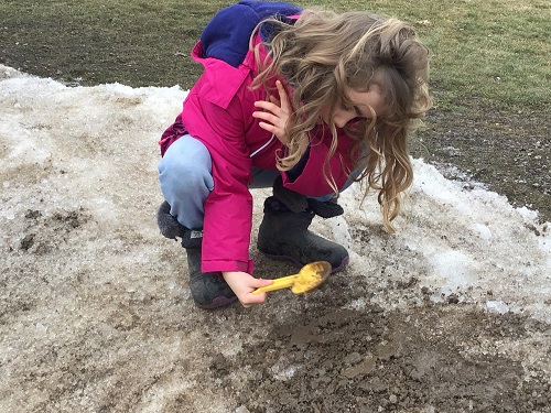 A child digging in the mud and snow bank
