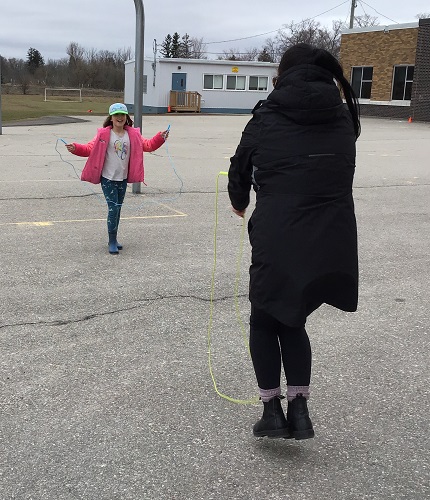 A child and an educator skipping outside