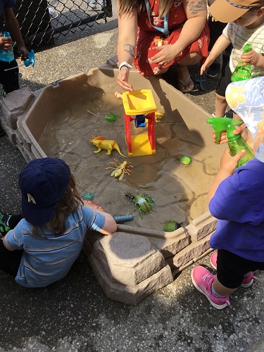 Children surrounding a water table outside