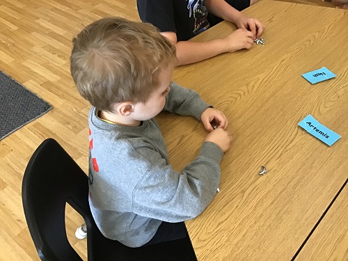 A child sitting at a table with nuts and bolts in front of him