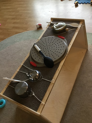 A shelf set up with utensils and metal pots and pans to bang on