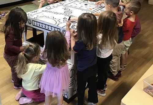 A group of children surrounding a cardboard bus 