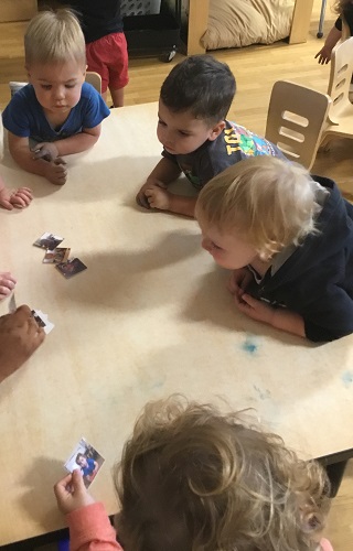 Children surrounding a table looking at their classmates pictures and names