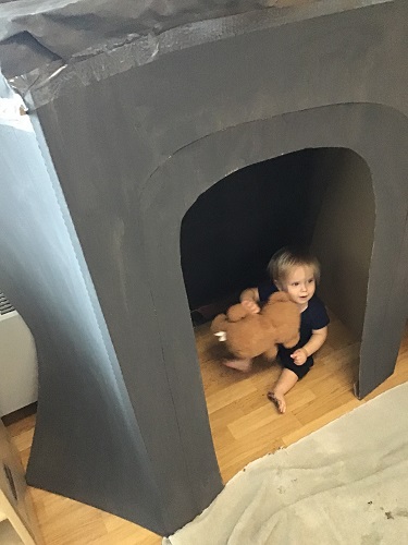 An infant holding a stuffed bear inside the cave