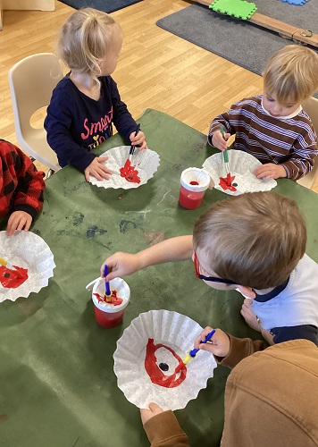 Children painting red poppies on coffee filters