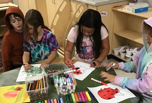 Children sitting at a table colouring Remembrance Day artwork