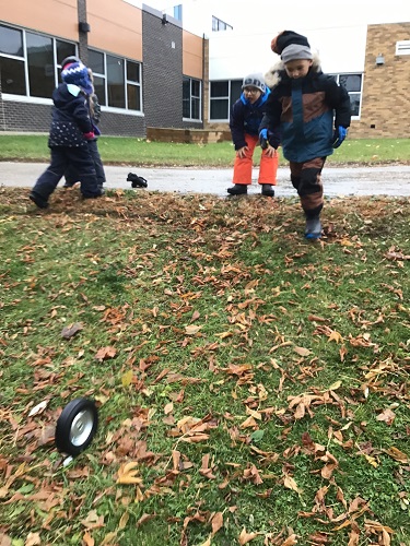 Children rolling a wheel down a small hill