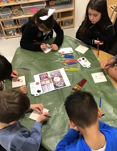 A group of children painting tiles at a table