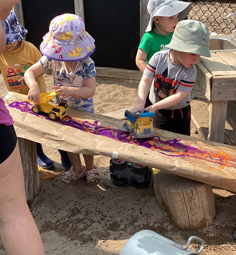 Children pushing cars down a ramp through paint