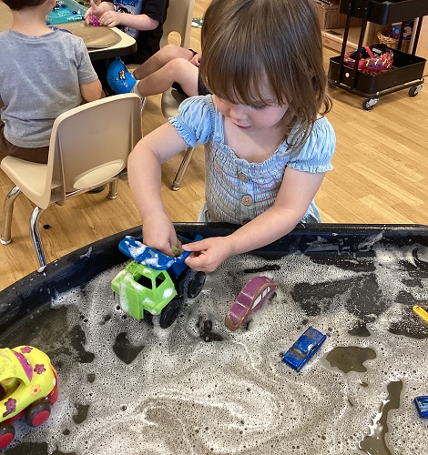 A child washing a truck in the soapy water