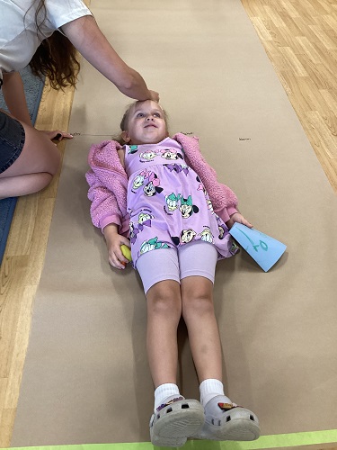 A child being measured by an educator on a long brown piece of paper
