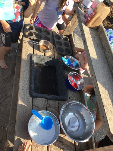Our mud kitchen set up with different bowls, pans and scoops