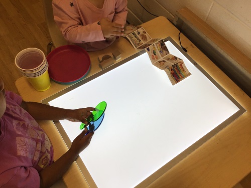 Children at a light table playing with colour wands