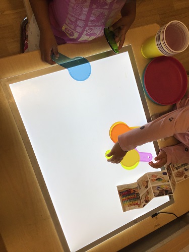 Children at a light table playing with colour wands