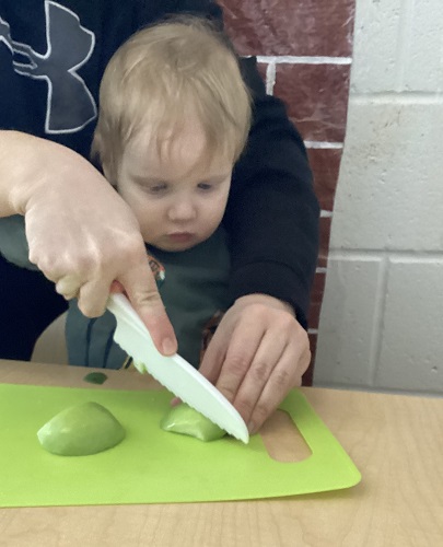 An educator and a child using a child safe knife to cut an apple