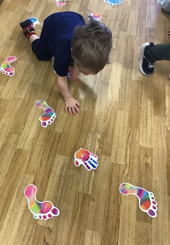 A child kneeling down looking at the pictures on the floor