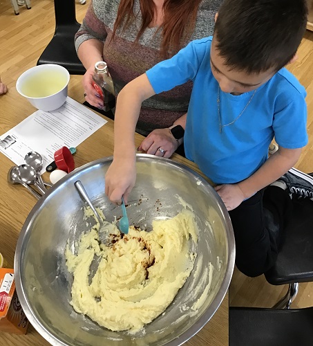 A child adding vanilla to a bowl of cookie dough