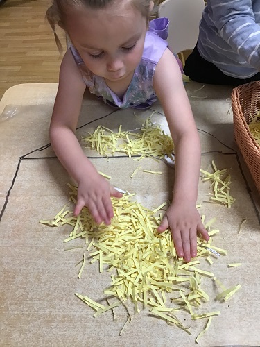 A child sticking yellow shredded paper to the Mac-Tac house