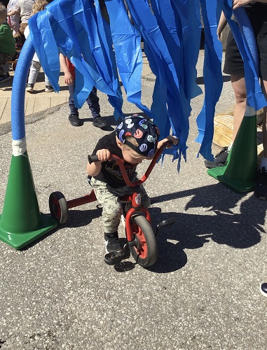 A child riding a bike through a homemade car wash