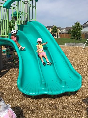 Children slidding down a slide at the park