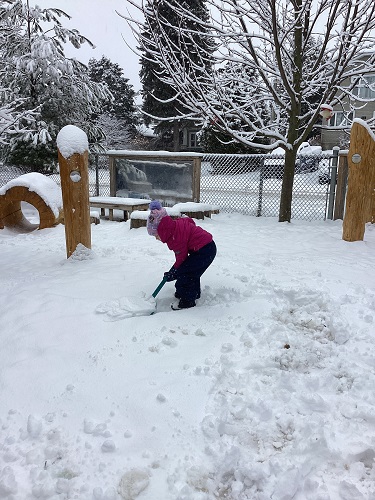 1 School Age 1 child shoveling the snow in the playground