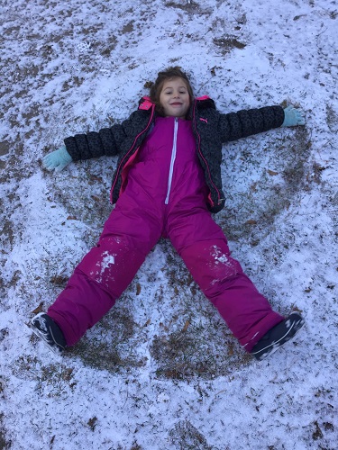 School age 1 child laying in the snow making a snow angel