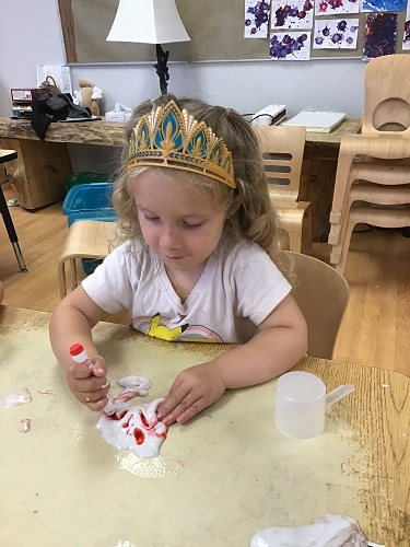 Preschool child using marker to colour the slime in her hands