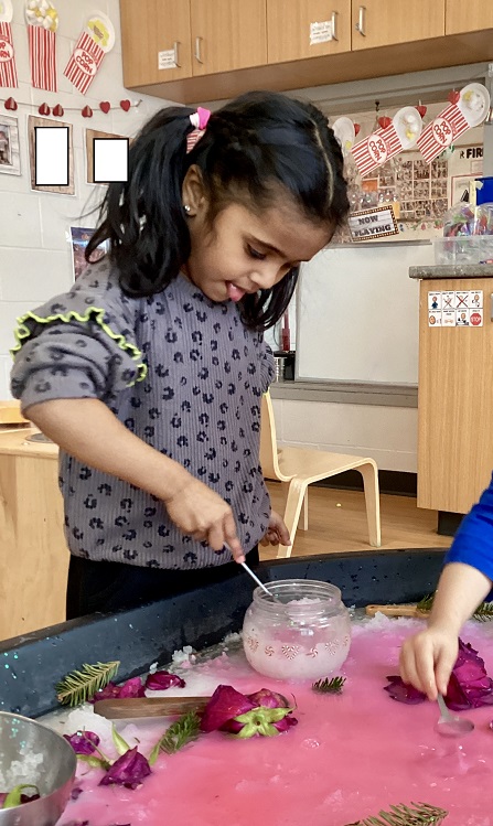 A preschool child scooping snow from a bowl at the tuff tray