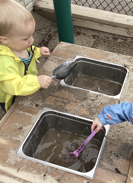 Toddler children mixing mud in the mud kitchen