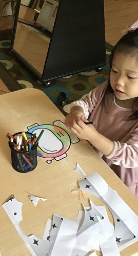 A preschooler is decorating a space helmet.