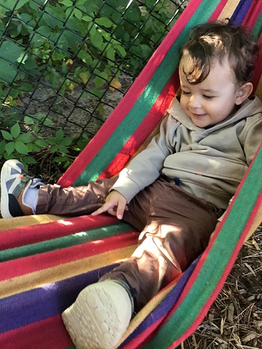 An infant is sitting in a hammock.